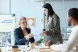 © Seventyfour - Portrait of senior female boss signing document in business meeting with team