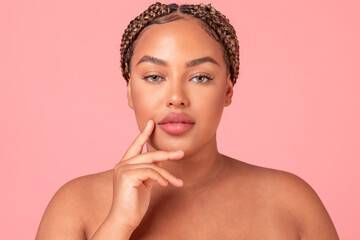 Closeup portrait of beautiful black body positive woman posing on pink studio background, enjoying her glow face skin