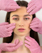 Hands in pink gloves doing makeup to a girl with green eyes Strong face Close up