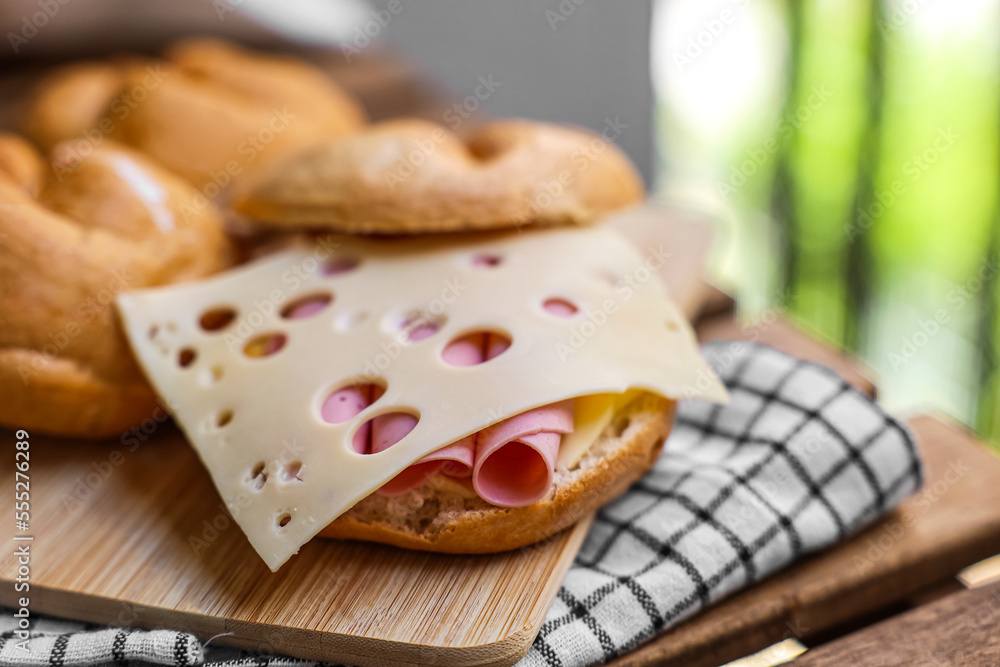 Delicious kaiser rolls with ham and cheese on wooden board