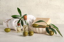 Bottles Of Oil, Green Olives, Soap Bar And Towels On Light Background
