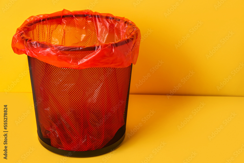 Rubbish bin with garbage bag on yellow background