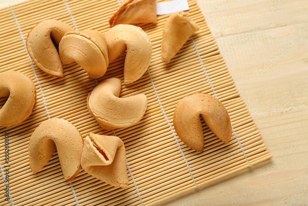 Bamboo mat with fortune cookies on wooden background, closeup