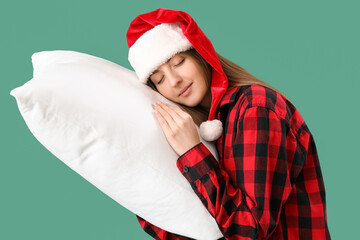 Canvas Print - Sleepy young woman in Santa hat with pillow on green background