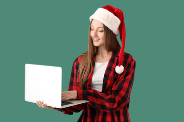 Sticker - Young woman in Christmas pajamas using laptop on green background