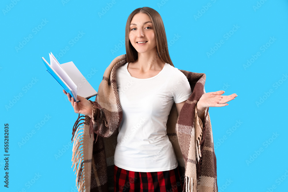 Young woman with plaid reading book on blue background