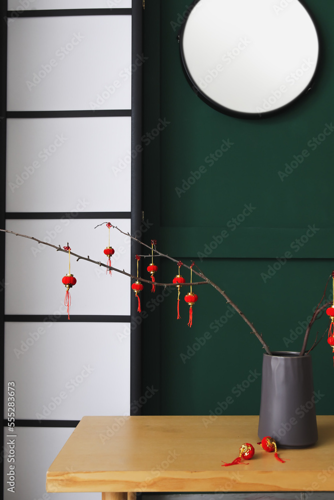 Vase with tree branches and decor for Chinese New Year celebration on table in room
