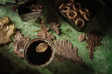 Wall Mural - Still life: a cup of coffee and brown roasted beans stand on a dark green background