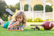 Summer games and outdoor activities for kids. Child playing chess game in spring backyard, laying on grass. Concentrated kid play chess. Kid playing board game outdoor.