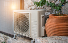 Air Heat Pump Outdoor Unit Against Wall Of Greek House.