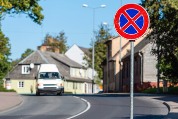 Wall Mural - small city street scene with a road sign in the foreground and defocused traffic in the background