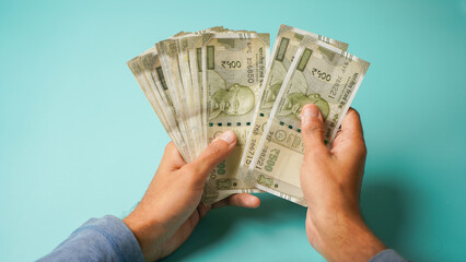 Unrecognizable hand counting five hundred Indian rupees, Close up of hand holding currency.