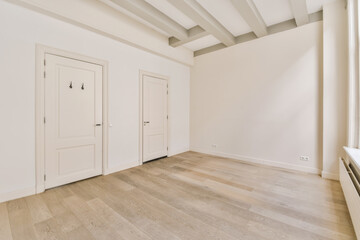 an empty room with white walls and wood flooring in the center of the room, there are two doors on either sides