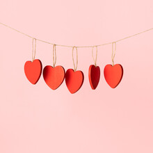Wooden Red Heart Ornaments Hanging On A Rope, Pink Background With Copy Space. Valentine Day Minimal Design In Square Shape