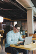 © Дмитрий Ткачук - A young promising man in casual clothes sits at a table and works on a laptop. Work space for remote work.