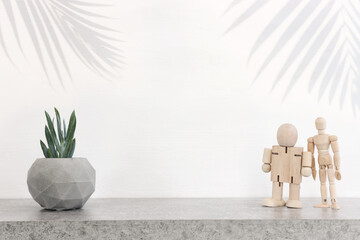 Wall Mural - Empty table with small plant and wooden dummy over white background