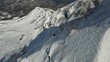 Mountain ski extreme sport sportsman freeride trick maneuver from snow summit ridge aerial view. FPV drone shot athlete racing speed adrenaline downhill slope freedom leisure winter recreation hobby