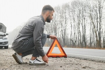 Wall Mural - Sad man on the road next to the broken car