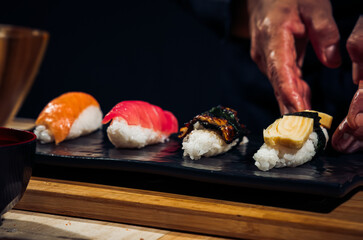 Wall Mural - Japanese chef making rice nigiri sushi with tuna, salmon, shrimp,traditional Japanese food ,Dark Tone