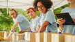 © Gorodenkoff - Portrait of a Happy Young Black Female Preparing Free Food Rations Together with Other Volunteers. Charity Workers and Members of the Community Work in Local Humanitarian Aid Donation Center.