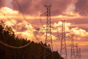 High voltage electricity power line towers near forest. Cloudy sky.  Transmission towers