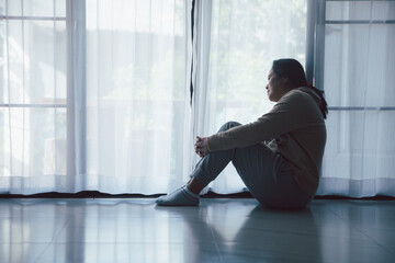Wall Mural - Schizophrenia with lonely and sad in mental health depression concept. Depressed woman sitting against floor at home with dark room feeling miserable. Women are depressed, fearful and unhappy.