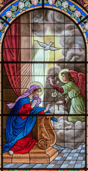 Wall Mural - DOMODOSSOLA, ITALY - JULY 19, 2022: The Annunciation on the stained glass in church Chiesa dei Santi Gervasio e Protasio by Luigi Fontana from 19. cent.