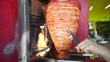 Wide Angle Slow Motion Of A Knife And Paint Scraper Turning And Slicing The Mexican Specialty Of Al Pastor Pork Which Is Fast Street Food.