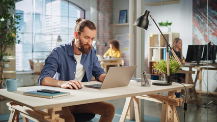 Poster - Creative Project Manager Sitting at a Desk, Working on a Laptop Computer in an Office. Boho Style Inspired Handsome Marketing Specialist Planning a Project, Browsing Internet and Writing Emails.