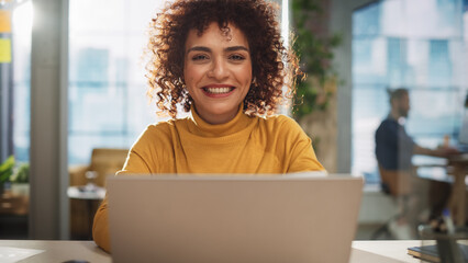 Fototapete - Portrait of an Attractive Arab Female in Creative Agency. Young Stylish Manager with Curly Hair Smiling, Looking at Camera. Manager Working in Modern Company.