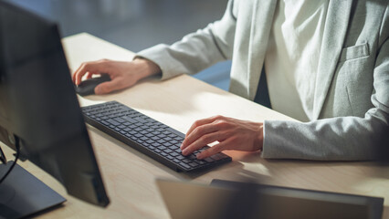 Fototapete - Young Male Employee in Gray Casual Jacket Working on Computer in Office During Daytime Close Up on Hands of a Manager Typing Texts on a Keyboard, Writing Text and Using Mouse.