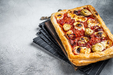 Vegetarian puff pastry pizza with artichoke, mozzarella, tomatoes and cheese. White background. Top view. Copy space