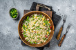 Chinese Fried rice with egg and vegetables in a wooden plate. Gray background. Top view