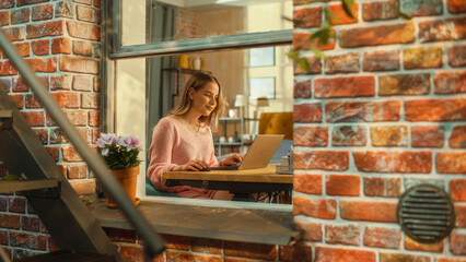 Poster - Beautiful Caucasian Girl Using a Laptop Computer while Sitting Behind a Desk in Brooklyn Style Brownstone House. Young Female Browsing Internet, Checking Social Media, Shopping Online.