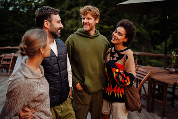 Group of cheerful multiethnic friends talking and laughing while standing outdoors