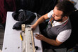 Middle eastern male tailor sews clothes on sewing machine at his tailoring studio