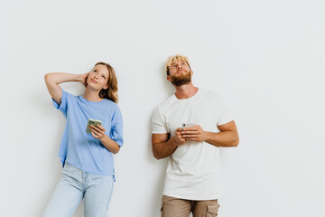 Wall Mural - White blond excited couple laughing while using mobile phones