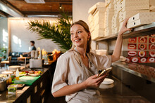 Smiling Young Woman Preparing Takeaway Food In Restaurant