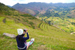 Female traveler taking photos from the mountain slope of Pisac archaeological park, Sacred valley of the Incas, Cusco region, Peru