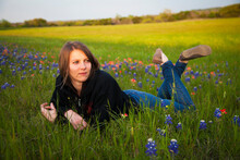 A Young Woman Laying In A Field Of Bluebonnet Wildflowers; Waco, Texas, United States Of America