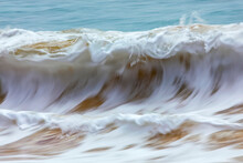 Motion Blur Of Foamy Rolling Waves Carrying Golden Sand At The Shore; Kihei, Maui, Hawaii, United States Of America