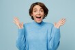 Young surprised overjoyed fun winner caucasian woman wear knitted sweater look camera spread hands say wow isolated on plain pastel light blue cyan background studio portrait People lifestyle concept