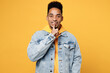 Young fun man of African American ethnicity wear denim jacket hoody look camera say hush be quiet with finger on lips shhh gesture isolated on plain yellow background studio. People lifestyle concept.