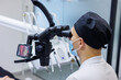 © DSMT - A dentist and an assistant treat a patient's teeth using a microscope. Professional teeth cleaning. Dental office. Dental microscope.