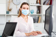 © JackF - Young female worker wearing medical facial mask engaged in business activities in office