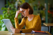 © Prostock-studio - Exhausted young woman using earpods and digital tablet at cafe