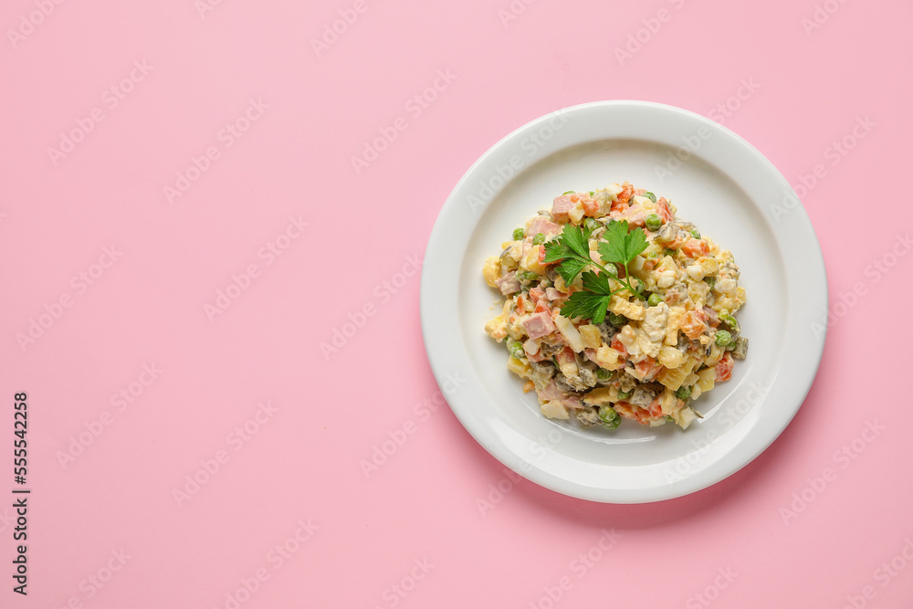 Plate with tasty Olivier salad on pink background