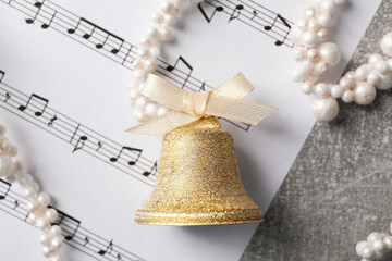 Sticker - Golden shiny bell with bow and music sheet on light gray table, flat lay. Christmas decoration