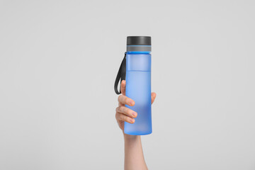 Wall Mural - Man holding transparent plastic bottle with drink on light grey background, closeup