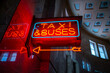 Bright vibrant red and blue city urban neon sign with arrow pointing to taxi and bus